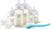 A set of baby bottles, pacifiers, and a bottle brush arranged on a white background. Produktbild-Vorschau