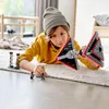 A young boy is playing with a LEGO Star Wars Sith TIE Fighter set on the floor. Produktbild-Vorschau