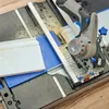 A Dremel cordless circular saw is being used on a saw table to cut a piece of white molding. Sawdust is visible on the table and the molding. Produktbild-Vorschau