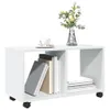 A white storage unit with two compartments, one holding books and the other empty, sits on black casters. A vase with yellow flowers and a cup of coffee with sugar cubes are on top. Náhled obrázku produktu