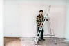 A man is standing on a ladder in a room that is being renovated. Náhled obrázku produktu