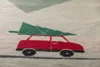 A close-up of a red car with a green Christmas tree on its roof, printed on a light gray fabric. Produktbild-Vorschau