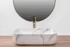 A marble-patterned vessel sink with a gold faucet is shown in front of a round mirror against a white wall. Produktbild-Vorschau