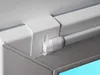 Close-up of a white curtain rod bracket and part of the rod, attached to a wall and a cabinet. Produktbild-Vorschau