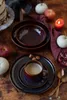 A rustic table setting with plates, a cup of coffee, and autumn decorations. Voir les images du produit