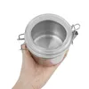 A hand holding a stainless steel storage container with a clear lid. Voir les images du produit