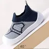 Navyblaue und weiße gestrickte Babyschuhe zum Laufenlernen mit weißer Gummisohle, auf schräger Fläche mit 40-Grad-Winkelangabe Anteprima dell’immagine prodotto