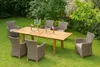 A dining set with chairs and a table is arranged on a grassy lawn in a garden setting. Produktbild-Vorschau