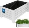 A white wooden planter box is shown from a diagonal angle, with a smaller image of the same planter filled with green plants and white flowers at the bottom right. Produktbild-Vorschau