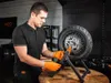A man in a workshop is working on a motorcycle wheel. Produktbild-Vorschau