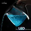 A hand is pouring water from a glass electric kettle with blue LED illumination into an unseen container against a dark background. Produktbild-Vorschau