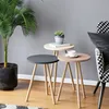 A set of three nesting side tables with a plant and a cup of coffee on them, next to a chair. Produktbild-Vorschau