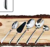A set of five stainless steel cutlery pieces arranged on a wooden surface with bark. Produktbild-Vorschau