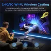 A young man is sitting on a couch, holding a smartphone and looking at a projector screen displaying a video game. The projector is on a table in front of the screen. Produktbild-Vorschau