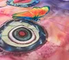 A close-up of a fabric with a printed butterfly and eye pattern. Produktbild-Vorschau