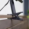 A close-up shot of a black clip attached to a wooden surface, likely part of a solar lamp. Produktbild-Vorschau