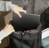 A person is placing a laptop into a black backpack. Produktbild-Vorschau
