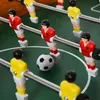 A close-up view of a foosball table with several player figures and the ball. Voir les images du produit