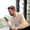 A man in a white shirt is looking at his phone while wearing a Bluetooth headset. Produktbild-Vorschau
