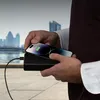 A person is holding a smartphone and a power bank, with a city skyline in the background. Náhľad obrázku produktu
