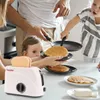 A family is making pancakes in the kitchen, with a toy toaster in the foreground. Anteprima dell’immagine prodotto