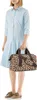 A woman stands against a white background, holding a leopard-print duffel bag. Náhled obrázku produktu