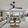 A living room with a ceiling fan, sofas, a coffee table, and a large window overlooking trees. Produktbild-Vorschau