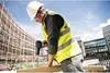 A construction worker is drilling into a piece of wood on a construction site. Voir les images du produit