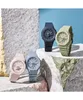Four Casio G-Shock watches in different pastel colors are arranged on textured surfaces against a blue background. Produktbild-Vorschau