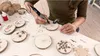 A person is using a Dremel tool to carve designs into wooden discs, which appear to be Christmas ornaments. Anteprima dell’immagine prodotto