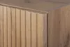 A close-up view of the corner of a wooden cabinet with a fluted door. Náhľad obrázku produktu