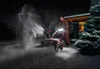 A man is using a snow blower at night in front of a house. Produktbild-Vorschau