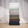 A stack of folded fitted sheets in various colors. Produktbild-Vorschau
