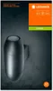 A dark gray wall with a dark gray outdoor wall lamp mounted on it. The lamp is cylindrical with rounded ends and has two light openings, one at the top and one at the bottom. The background is textured dark gray, resembling concrete. An orange box with the Produktbild-Vorschau