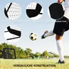 A person kicking a soccer ball near a soccer rebounder net on a grassy field. Voir les images du produit