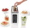 A toaster with bread being inserted, accompanied by breakfast items like berries, honey, and a drink. Náhled obrázku produktu