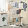 A multi-level clothes drying stand with laundry and shoes on it, next to a washing machine. Produktbild-Vorschau