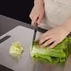 A person is cutting lettuce on a stainless steel cutting board. Produktbild-Vorschau