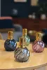 Four decorative glass diffusers with gold caps are arranged on a wooden table in a living room setting. Produktbild-Vorschau