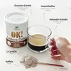 A can of OK! FatBurn Coffee, a cup of coffee, and a scoop of powder are arranged on a white surface, with labels pointing to the ingredients. Podgląd zdjęcia produktu
