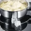 A stainless steel pot with pasta boiling inside sits on a black induction stovetop. Three ice cubes are placed in front of the pot. Náhľad obrázku produktu