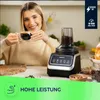 A woman is holding a cup of coffee next to a coffee grinder. Anteprima dell’immagine prodotto
