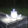 A white LED solar lamp with foldable panels is placed on a stone surface outdoors at night, with trees in the background. Anteprima dell’immagine prodotto