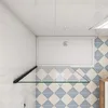A top-down view of a shower tray and a glass shelf in a bathroom with tiled walls and floor. Produktbild-Vorschau