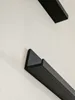 A close-up view of two black shelves mounted on a textured white wall. Produktbild-Vorschau