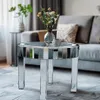A mirrored round coffee table with a vase of flowers and a decorative sphere on top, placed in a living room setting with a sofa in the background. Anteprima dell’immagine prodotto