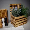 A wooden crate with plants and kitchen accessories on a table. Produktbild-Vorschau