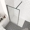 A modern bathroom corner with a walk-in shower, white subway tiles on the walls, and a black and white geometric pattern on the floor. Produktbild-Vorschau