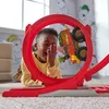 A young boy is lying on the floor, laughing as a toy monster truck goes through a red loop. Náhľad obrázku produktu