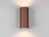 A brown cylindrical wall light mounted on a light gray wall, with light emanating from the top and bottom. Voir les images du produit